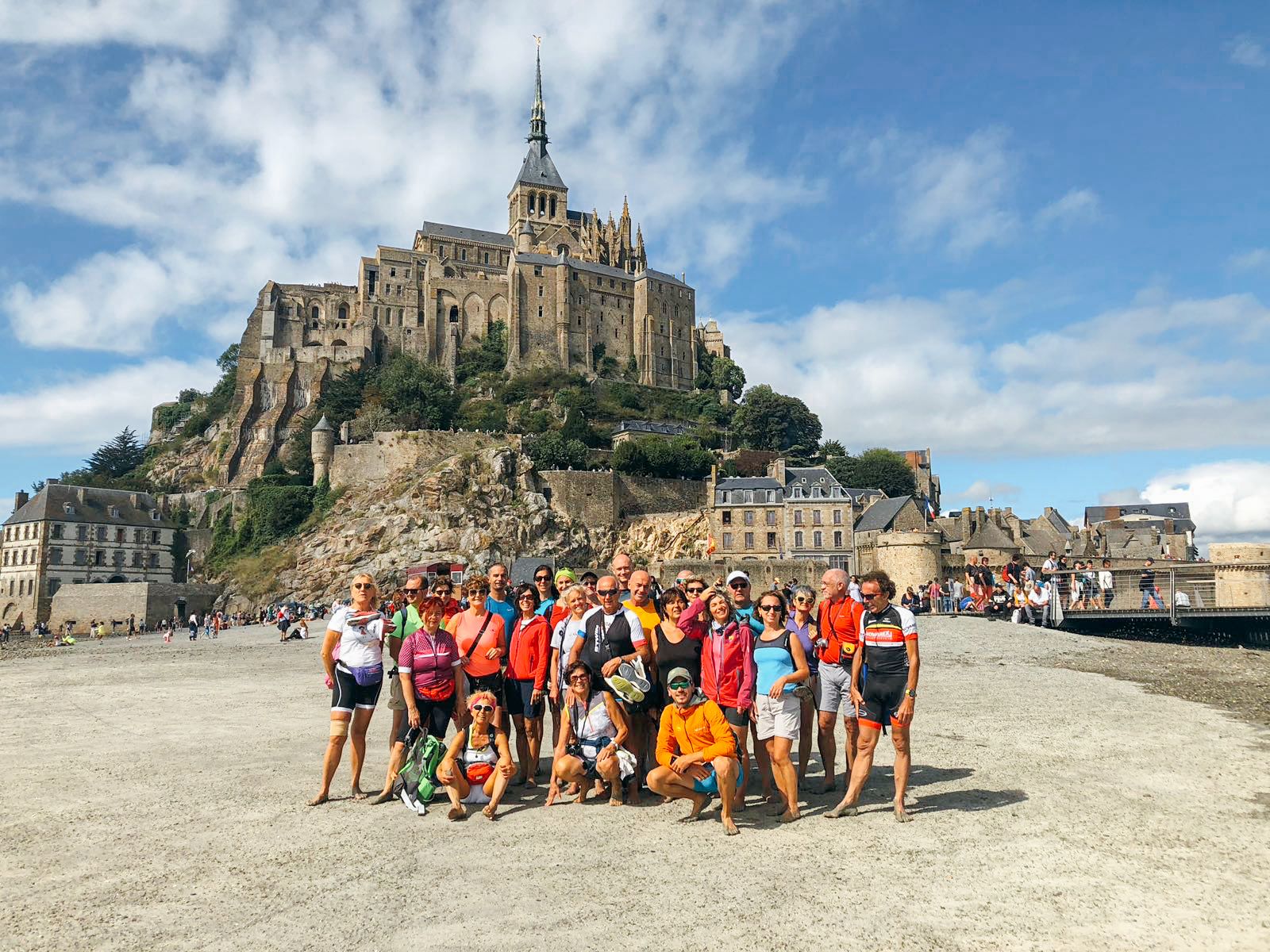 Gruppo di viaggiatori davanti a Mont Saint-Michel, con la famosa abbazia visibile sullo sfondo.